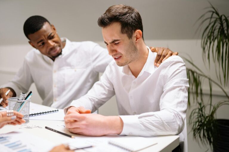 Coworkers showing emotional support in a modern office environment.
